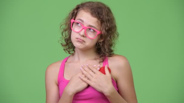 Young sad nerd woman holding heart while looking down — Stock Video