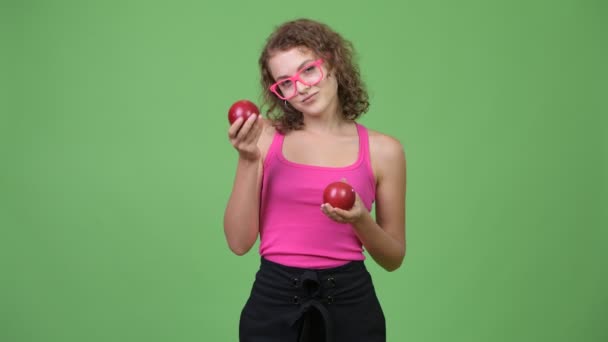 Jonge mooie nerd vrouw toont twee rode appels — Stockvideo