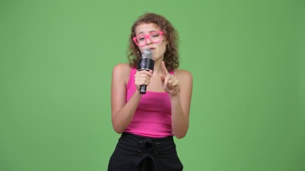 Unga glada vackra nörd kvinna sjunger med mikrofon — Stockvideo