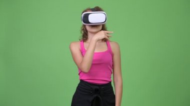 Kıvırcık sarı saçlı chroma anahtar yeşil arka plana sahip karşı gözlük takan genç güzel inek kadınla stüdyo çekim