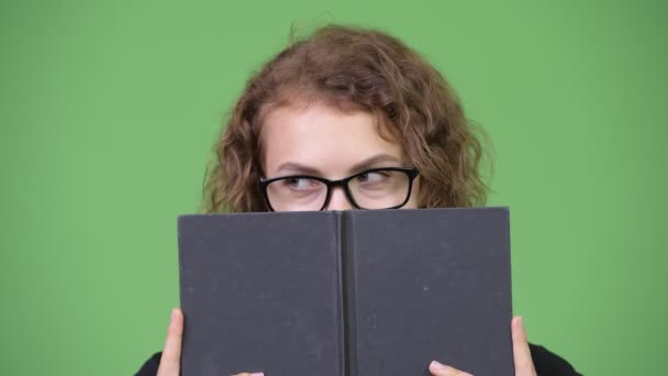 Νέοι όμορφη nerd γυναίκα που καλύπτουν το πρόσωπο με το βιβλίο — Αρχείο Βίντεο