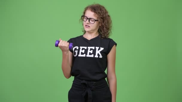 Jonge nerd vrouw trainen met halters tegen groene achtergrond — Stockvideo