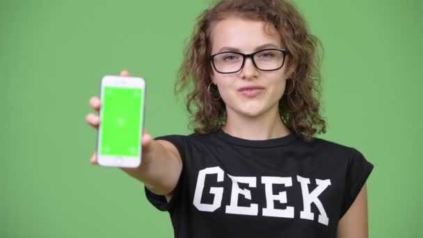Junge glückliche schöne Nerd-Frau zeigt Telefon — Stockvideo