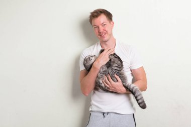 Tutarak şirin kedi gülümseyen mutlu yakışıklı delikanlı
