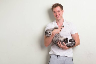 Tutarak şirin kedi gülümseyen mutlu yakışıklı delikanlı