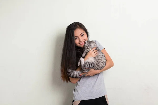 Junge glückliche schöne asiatische Frau lächelt, während sie süße Katze hält — Stockfoto