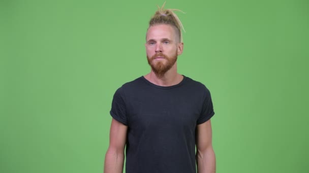 Knappe bebaarde man met dreadlocks op zoek geschokt terwijl die betrekking hebben op mond — Stockvideo