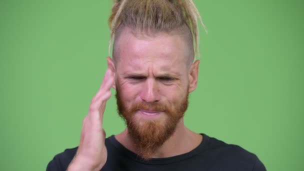 Напружений бородатий чоловік з дредлоками має головний біль — стокове відео