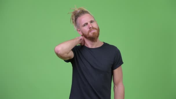 Напружений бородатий чоловік з дредлоками має біль в шиї — стокове відео