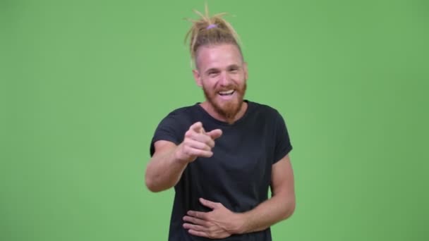 Homem barbudo bonito feliz com dreadlocks rindo enquanto aponta para a câmera — Vídeo de Stock