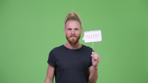 Glücklich schöner bärtiger Mann mit Dreadlocks schreit Selfie mit Papierschild — Stockvideo