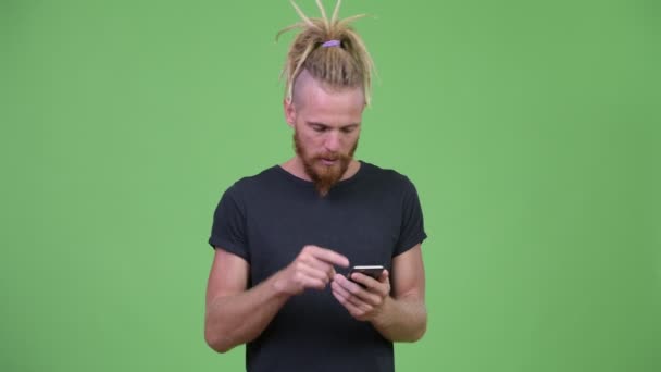 Bonito barbudo com dreadlocks usando telefone e recebendo más notícias — Vídeo de Stock
