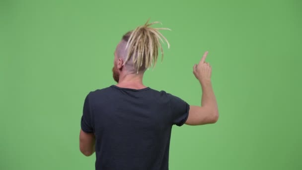 Вид сзади бородатого человека с дредами, указывающими пальцем — стоковое видео