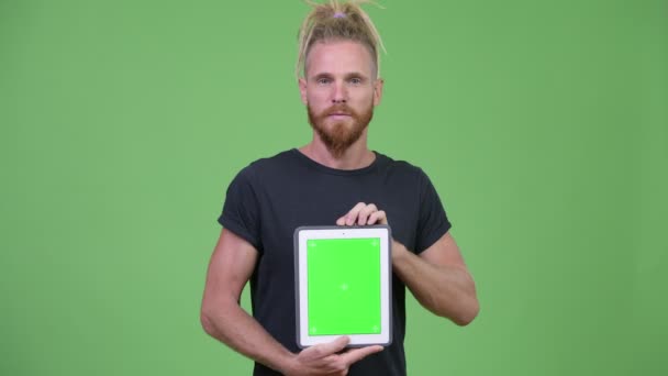 Щасливий красивий бородатий чоловік з дредлоками, що показують цифровий планшет — стокове відео