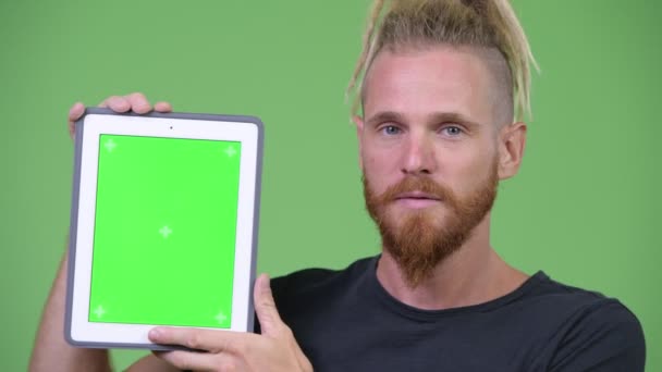 Happy handsome bearded man with dreadlocks showing digital tablet — Stock Video