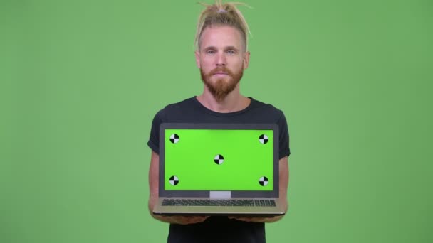 Ευτυχισμένος όμορφος γενειοφόρος άνθρωπος με dreadlocks δείχνει φορητό υπολογιστή — Αρχείο Βίντεο