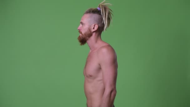 Vue du profil de bel homme barbu musclé avec dreadlocks regardant à la caméra torse nu — Video