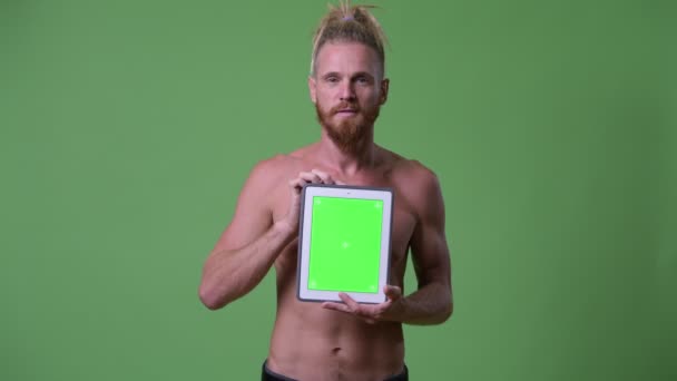 Ευτυχισμένος όμορφος μυϊκή γενειοφόρος άνδρας με dreadlocks δείχνει ψηφιακή δισκίο shirtless — Αρχείο Βίντεο