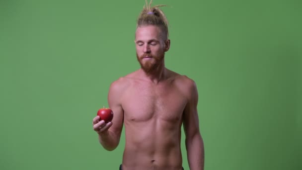 Schöner muskulöser bärtiger Mann mit Dreadlocks, der Apfel ohne Hemd gibt — Stockvideo