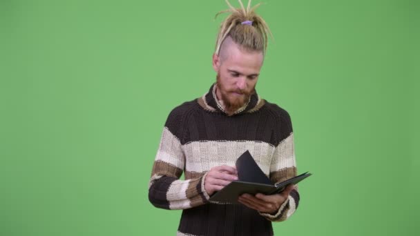 Schöner bärtiger Mann mit Dreadlocks, der in warmer Kleidung Buch liest — Stockvideo