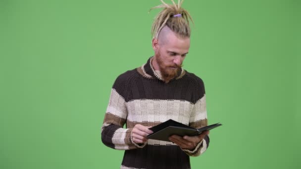 Feliz hombre barbudo guapo con ropa abrigada pensando mientras lee el libro — Vídeos de Stock