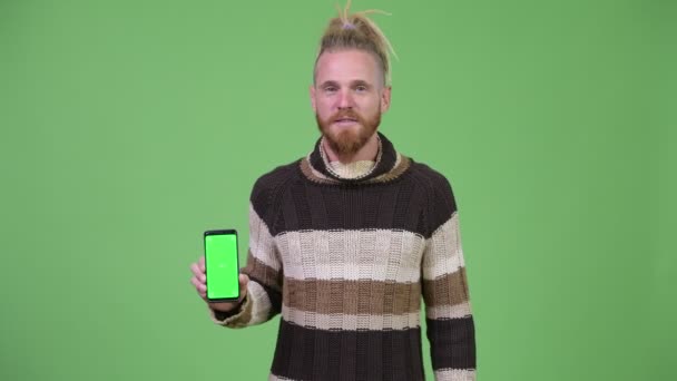 Heureux bel homme barbu montrant téléphone et donnant pouces vers le haut — Video