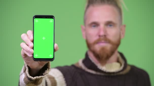 Bonito homem barbudo feliz sorrindo ao mostrar telefone — Vídeo de Stock