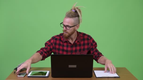 Stilig skäggiga hipster mannen multi-tasking arbete mot träbord — Stockvideo