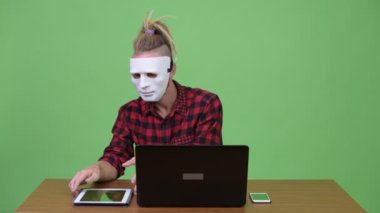 Hipster adam maskeli hacker çoklu görev iş ahşap masa karşı süre olarak
