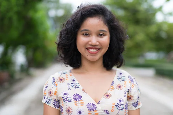 Açık havada gülümseyen kısa kıvırcık saçlı güzel Asyalı kadın