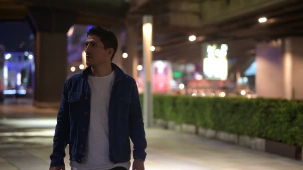 Латиноамериканец думает, исследуя улицы города ночью — стоковое видео
