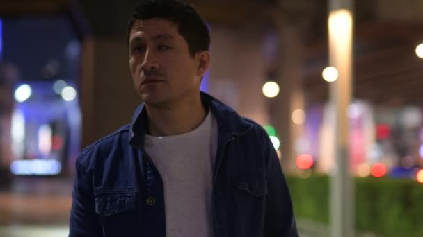 Латиноамериканец думает, исследуя улицы города ночью — стоковое видео