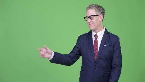 Студійний знімок щасливого зрілого бізнесмена стукає пальцями і показує щось — стокове відео