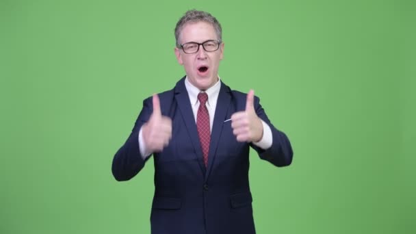 Студійний знімок щасливого зрілого бізнесмена, який виглядає збудженим, даючи великі пальці вгору — стокове відео