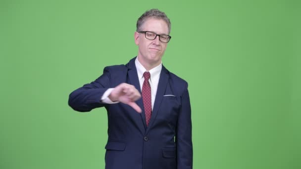 Studio shot of sad mature businessman giving thumbs down — Stock Video