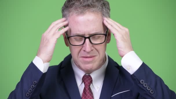 Студийный снимок стресса зрелого бизнесмена, страдающего головной болью — стоковое видео