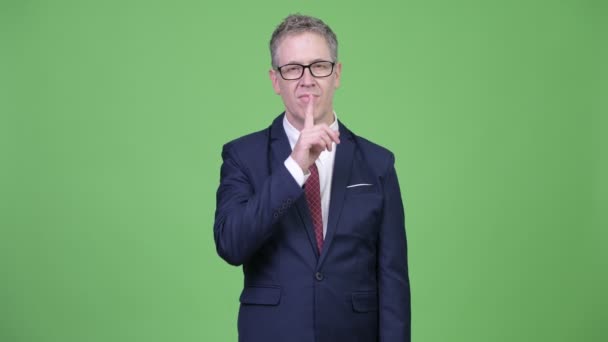 Studio shot van rijpe zakenman met de vinger op de lippen — Stockvideo