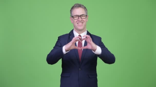 Studio shot of happy mature businessman giving hand heart gesture — Stock Video