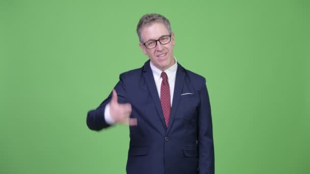 Студійний знімок щасливого зрілого бізнесмена з викликом мені жестом — стокове відео