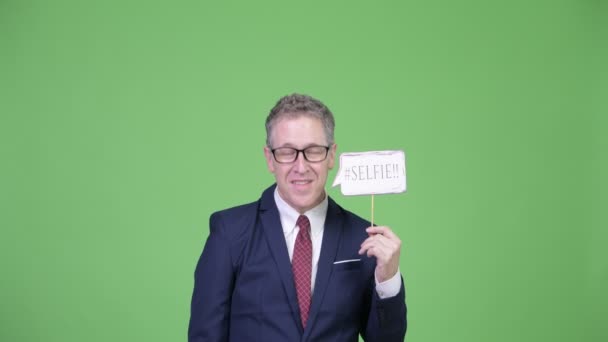 Estudio de tiro de feliz hombre de negocios maduro con selfie papel signo — Vídeo de stock