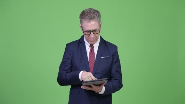 Студийный снимок зрелого бизнесмена, мыслящего с помощью цифрового планшета — стоковое видео