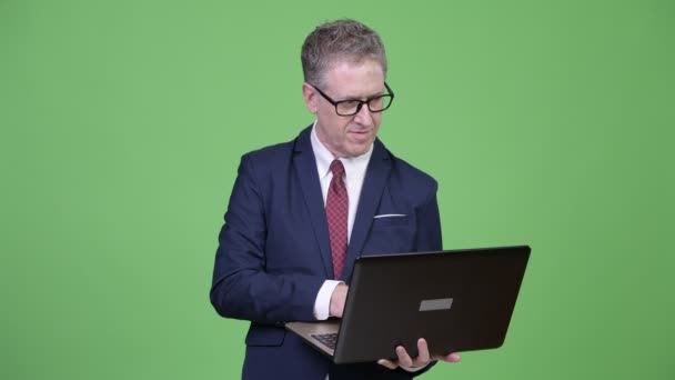 Studio shot of mature businessman thinking while using laptop — Stock Video