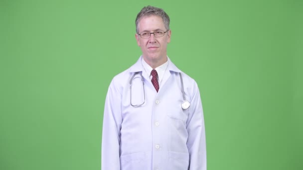 Portrait of mature man doctor thinking while wearing eyeglasses — Stock Video