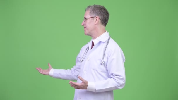 Porträt eines reifen Mannes Arzt präsentiert etwas — Stockvideo