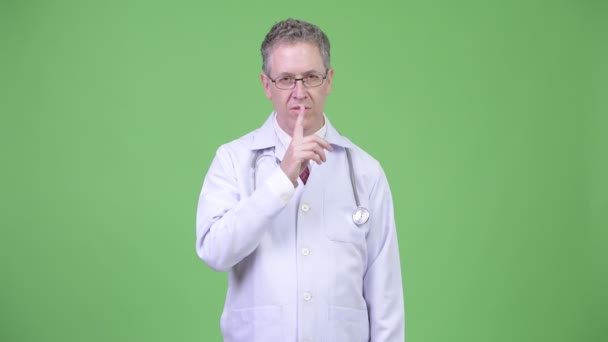 Portrait of mature man doctor with finger on lips — Stock Video