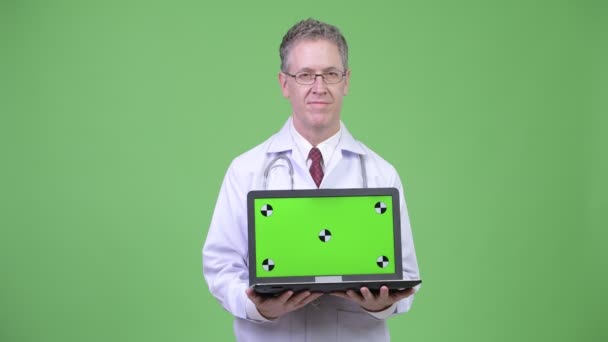 Portret van gelukkig volwassen man arts toont laptop — Stockvideo