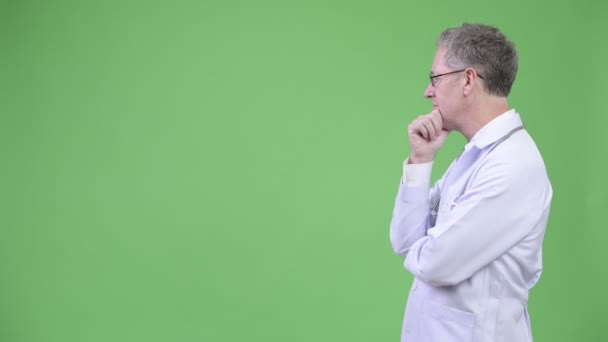 Profile view of mature man doctor thinking while wearing eyeglasses — Stock Video