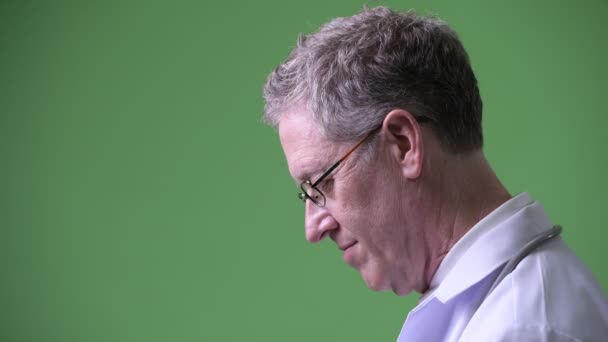 Profile view of mature man doctor with eyeglasses looking up — Stock Video