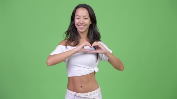 El kalp işaret gösteren genç mutlu güzel çok etnik gruptan oluşan bir kadın — Stok video