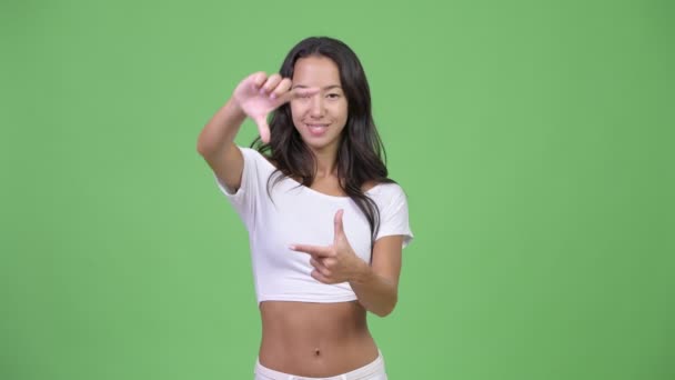 Junge glückliche schöne multiethnische Frau, die sich mit den Fingern konzentriert — Stockvideo